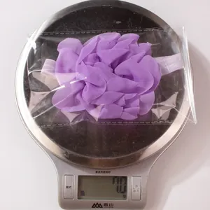 Dettaglio della fascia floreale leggera viola per neonati pesata su bilancia digitale