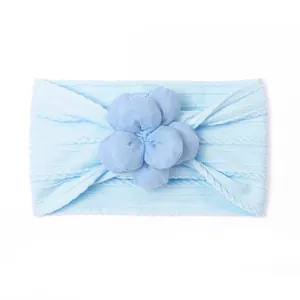 Détail d'un bandeau bébé en maille avec fleur 3D et texture tressée sur nylon doux