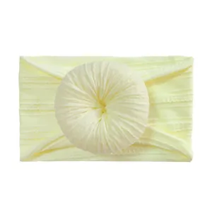 Detail of light yellow nylon baby headband with large jacquard donut flower knot