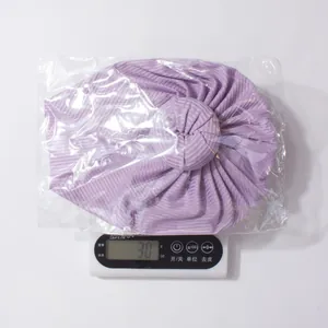 Vue détaillée du bonnet bébé violet côtelé sur une balance pesant environ 30 grammes