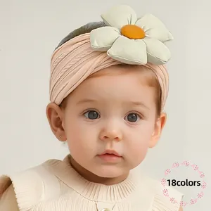 Bandeau bébé rose côtelé orné d'une grande fleur de couleur crème au centre orange