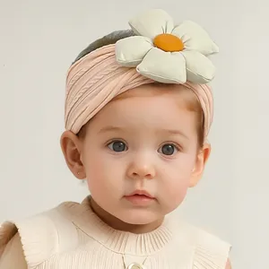 Détail d'un bandeau rose pour bébé avec fleur de marguerite en peluche et maille douce