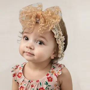 Detailed close-up of baby lace headband with large floral embroidery bow and elastic band