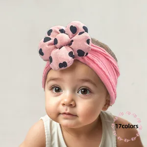 Detail of pink stretch baby headband with a large heart-print floral decoration