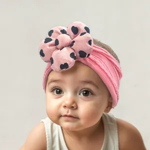 Close-up of pink elastic baby headband with large black heart pattern floral detail