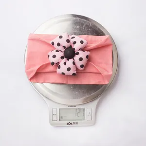 Close-up showing a pink floral baby headband weighing 12.1g on a digital scale