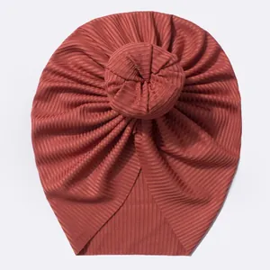 Détail du bonnet turban bébé rouge rouille avec nœud donut et texture maille côtelée