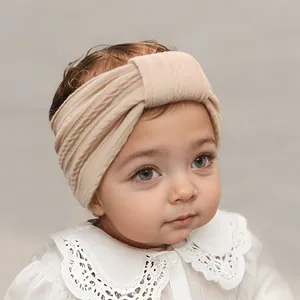 Detail of nude pink ribbed baby headband with elegant knot design on infant model