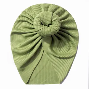 Détail d'un turban pour bébé côtelé vert clair avec un grand nœud donut élégant