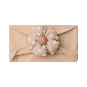 Detail of soft elastic baby headband featuring a pink polka dot flower and fabric texture