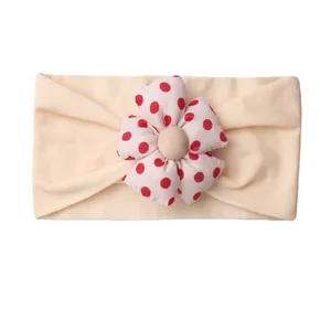 Cute baby headband with red polka dot flower decoration on soft beige elastic fabric