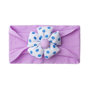 Detail of soft lavender elastic baby headband featuring a large blue polka dot floral motif