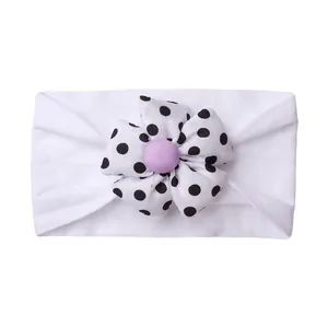 Detail of baby headband with a black and white polka dot flower and purple button
