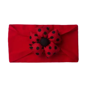 Detail of red baby headband with 3D polka dot flower made of soft elastic cotton fabric
