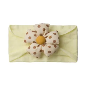 Detail of baby headband featuring a large 3D flower with brown polka dots on a yellow band