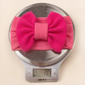 Detailed view of large rose red waffle knit bow headband on a digital scale weighing 19.4g