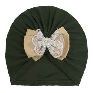 Detail van baby tulband muts met een grote kanten strik en elegante witte parel accenten