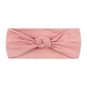 Fascia per capelli neonata in maglia a coste rosa con nodo decorativo su sfondo bianco