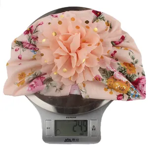 Detailed view of lightweight baby floral turban hat weighing 24.9 grams on a digital scale