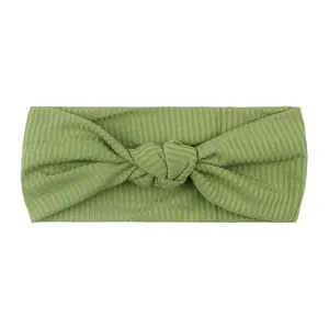 Dettaglio della fascia per neonati in maglia a coste verde salvia con un morbido nodo decorativo