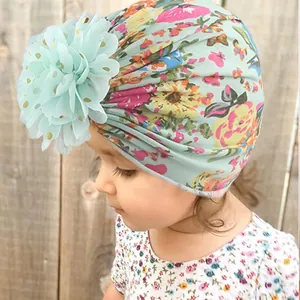 Close-up of a light green baby turban hat with colorful floral print and large chiffon flower