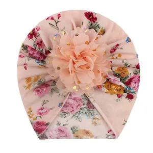 Detail of baby turban hat featuring pink floral pattern and gold polka dot mesh flower