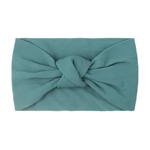 Detailed close-up of wide knotted nylon baby headband in teal green knit fabric