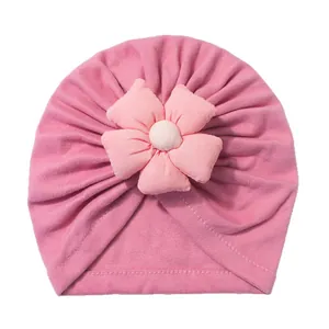 Pink knit baby turban hat with a 3D five-petal fabric flower on a white background