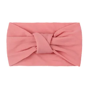 Close-up of soft peach pink knitted baby headband featuring a textured knotted design