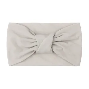 Detailed close-up of soft beige knot-style nylon headband with elastic matte texture fabric