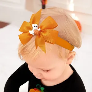 Détail d'un bandeau d'Halloween pour bébé avec nœud orange et breloque fantôme avec citrouille