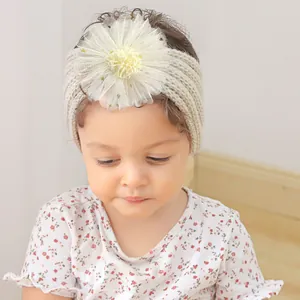 Détail d'un bandeau pour bébé en maille crème orné d'une grande fleur en tulle jaune