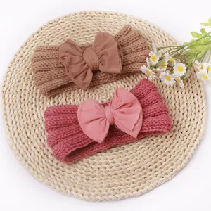 Detail der Strickstruktur und Stoffschleifen an braunen und rosa Baby-Haarbändern