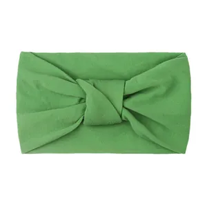 Close-up of grass green knotted nylon baby headband with soft knitted texture