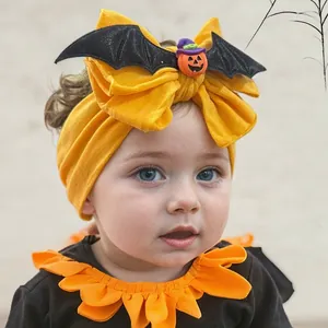 Detail of yellow nylon baby headband with pumpkin charm and black bat wings for Halloween