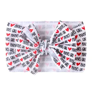 Dettaglio fascia neonata bianca con scritta MAMA'S GIRL e fiocco cuore rosso