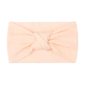Close-up of soft knitted nylon baby headband with knot detail in blush pink color