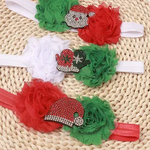 Three Christmas baby headbands with chiffon flowers and Santa motifs on beige background