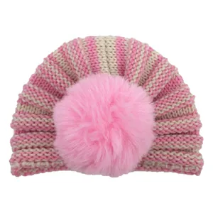 Detail of baby knit hat featuring pink stripes and a large soft faux fur pom-pom ball