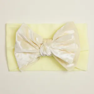 Détail d'un bandeau jaune en velours avec nœud papillon élastique pour bébé