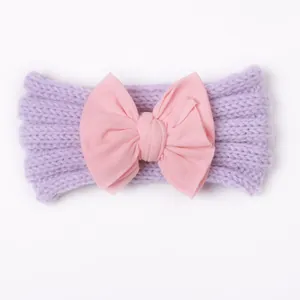 Detailaufnahme des gestrickten lila Baby-Stirnbands mit großer rosa Stoffschleife