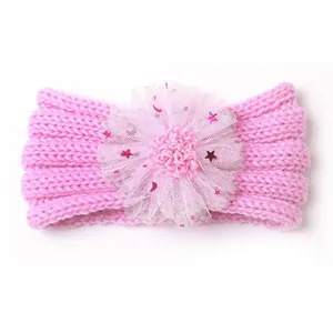 Détail d'un bandeau en maille rose pour bébé avec une grande fleur en dentelle et paillettes