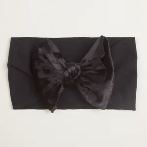 Gros plan d'un grand nœud en velours noir sur un bandeau élastique en nylon pour bébé