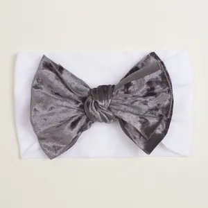 Détail du nœud en velours gris foncé sur un bandeau en nylon blanc élastique