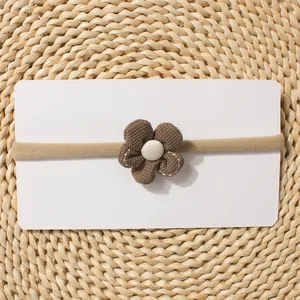 Detailed macro view of a soft brown knitted flower on a thin elastic baby headband