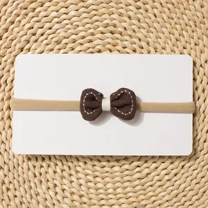 Detail of dark brown bow headband with white stitching on soft elastic band