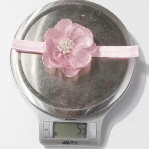 Detailopname van een roze bloemen babyhoofdband met witte parels op een digitale weegschaal