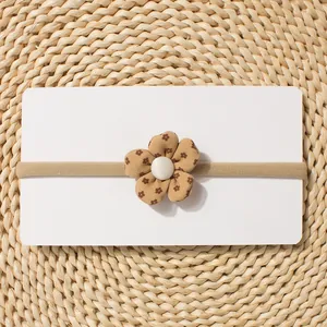Close-up of khaki elastic baby headband with floral fabric flower and pearl accent