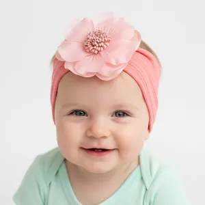 Detail of pink silk flower and coral ribbed elastic headband on an infant baby