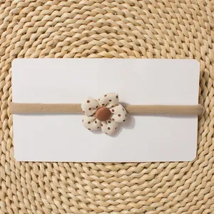 Detail of baby elastic headband with polka dot fabric flower on display card
